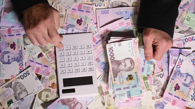 Counting Ukrainian hryvnia banknotes with calculator on table. finance, economic calculation. Business, paper money and calculation. profit savings, financial planning. money cash recalculation.