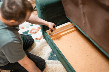 Man disassembling sofa furniture mechanism at home using furniture wrench. DIY Assembling Furniture concept.