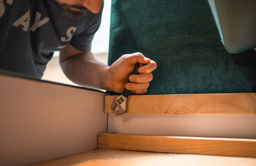 Man disassembling sofa furniture mechanism at home using furniture wrench. DIY Assembling Furniture...