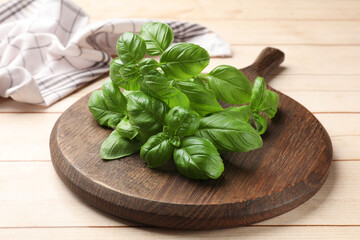 Fresh basil leaves on light wooden table, closeup