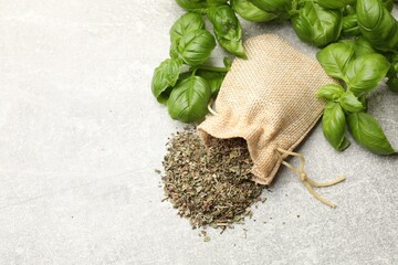 Obraz premium Fresh and dry basil leaves on light grey table, flat lay. Space for text