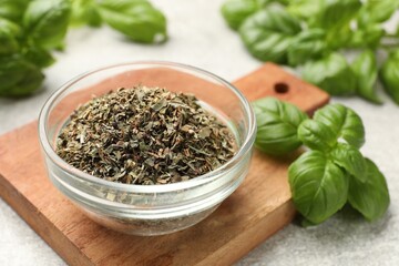 Fresh and dry basil leaves on light grey table, closeup