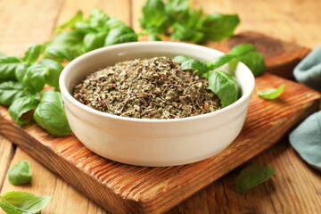 Dry basil in bowl and fresh green leaves on wooden table, closeup