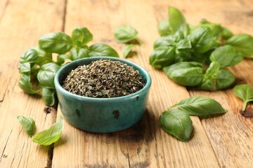 Dry basil in bowl and fresh green leaves on wooden table, closeup