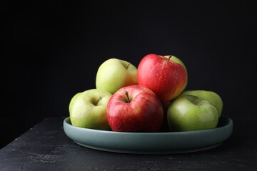 Fresh red and green apples on dark textured table against black background, closeup. Space for text
