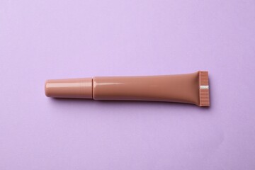 Beautiful nude lip gloss on lilac background, top view