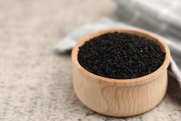 Aromatic black caraway in wooden bowl on grey table, closeup. Space for text