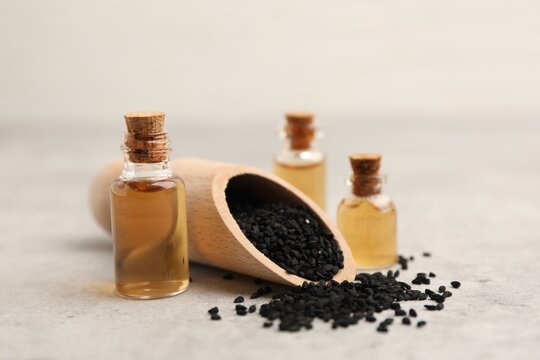 Black cumin seeds and oil on light grey table, closeup - Powered by Adobe