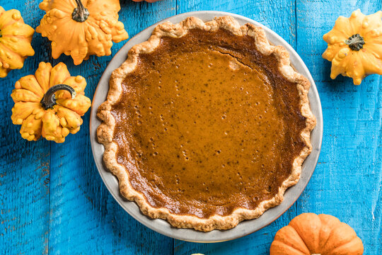Top view of classic pumpkin pie with spices and ingredients arranged around