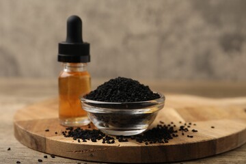 Black cumin seeds and oil on wooden table, closeup. Space for text