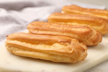 Fresh tasty eclairs on light table, closeup