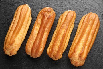 Tasty eclairs on black table, top view