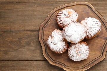 Tasty profiteroles with powdered sugar on wooden table, top view. Space for text