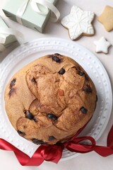 Tasty Christmas panettone cake, gingerbread cookies and gifts on table, flat lay