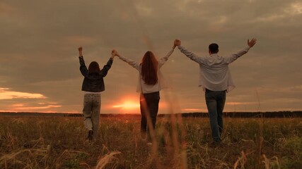 Happy family, arms raised, enjoys walk in park on green grass. Family game, teamwork. Team lifestyle of father mother, child. Dad mom, child daughter, traveling in nature. Family business, teamwork