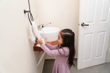 Little girl drying hands with towel in home bathroom
