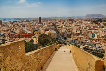 A panoramic view of a sprawling city seen from a descending stone path.
