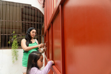 Mother and little daughter opening home gate