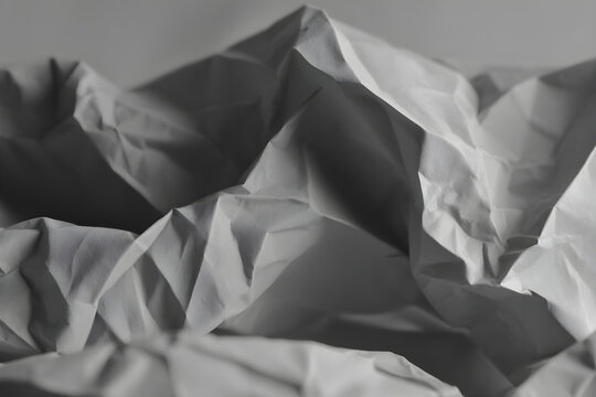 Abstract textured background of crumpled white paper with dramatic lighting.