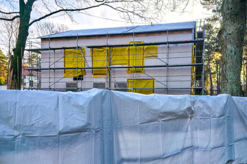 Construction site with scaffolding and plastic sheeting covering residential building renovation