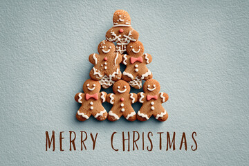 Fototapeta premium Świąteczna kartka z choinką ułożoną z piernikowych ludzików w stylu piramidy. Napis 