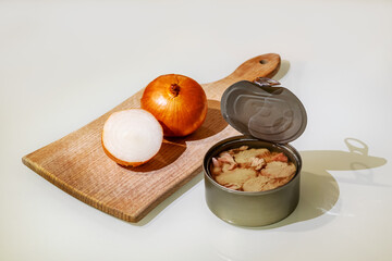Fresh and soft canned tuna on the table, with a cutting board and onion
