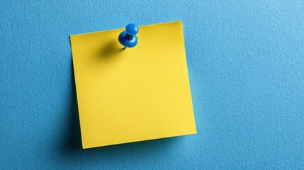 A bright yellow sticky note is fastened with a blue push pin to a smooth blue surface, providing a simple yet effective reminder tool for notes and messages.