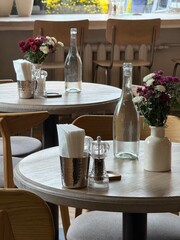 Cozy Cafe Interior with Flowers and Glass Bottles on Wooden Tables