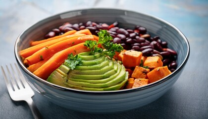 fresh and colorful healthy bowl with sliced avocado cooked sweet potatoes black beans carrot slices and fresh parsley ready to eat