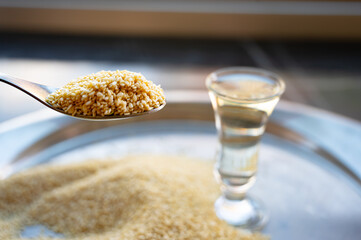 Sesame seeds in a spoon with a glass of sesame oil — close-up