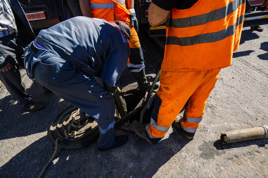 Sewer workers cleaning manhole and unblocking sewers