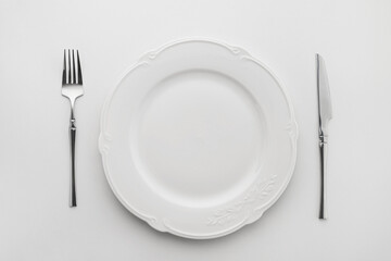 White plate with cutlery on a white background, table setting