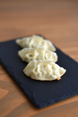 Three gyozas on black slate board
