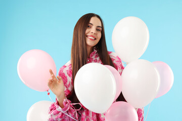 Beautiful woman with balloons on light blue background