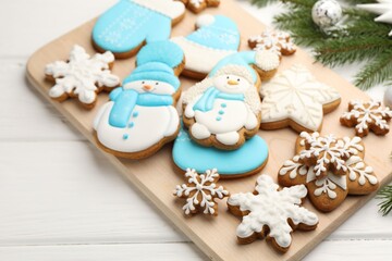 Tasty gingerbread cookies and Christmas decor on white wooden table, closeup