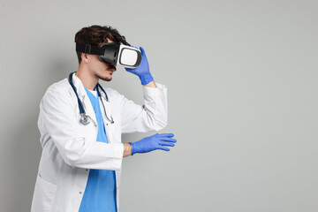 Modern technology. Doctor using virtual reality headset on grey background. Space for text