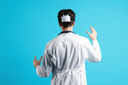 Modern technology. Doctor using virtual reality headset on light blue background, back view