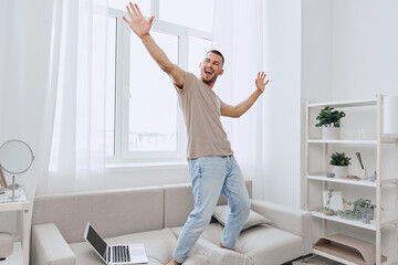 Happy man dancing joyfully in a bright, minimalistic living room, embracing a lifestyle of digital detox and emotional minimalism.