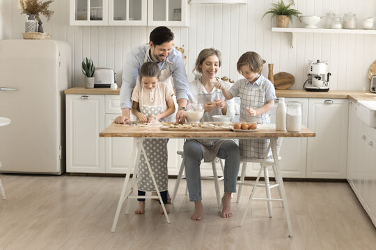 Couple with two diverse young kids cook dumplings at kitchen