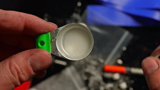 Drug user preparing liquid drugs in the tin cooker container used for mixing and heating a drug with lighter. Drug such as cocaine, white heroin or crack cocaine mixed and dissolved with water.
