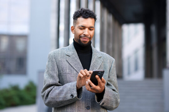 Handsome man in suit with smartphone on city street