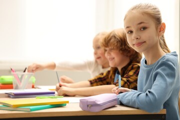 Fototapeta premium Happy children at desk in classroom. Space for text