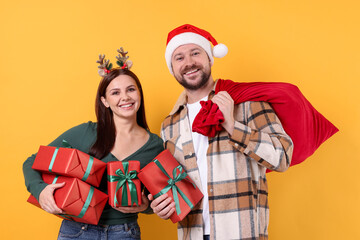 Happy couple with Christmas gifts on yellow background