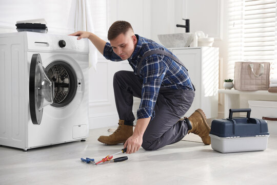 Repairman fixing broken washing machine at home