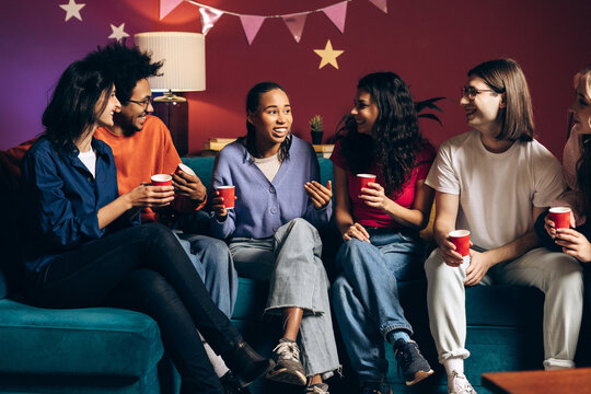 Diverse group of multiracial friends talking and laughing at house party - Powered by Adobe
