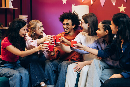 Diverse group of smiling multinational young adults friends toasting at cheerful party - Powered by Adobe