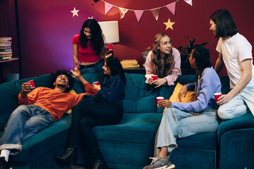 Diverse group of smiling multinational friends socializing at lively home party