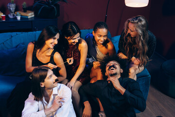 Group of diverse friends having fun at a party laughing with photobooth props