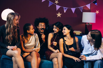 Diverse young friends celebrating a fun house party laughing together