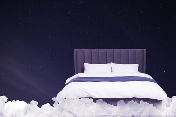 Fototapeta premium Large bed on fluffy clouds in starry night sky
